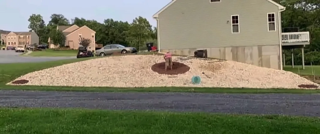 After: the same slope covered in light river stone with mulch planting rings