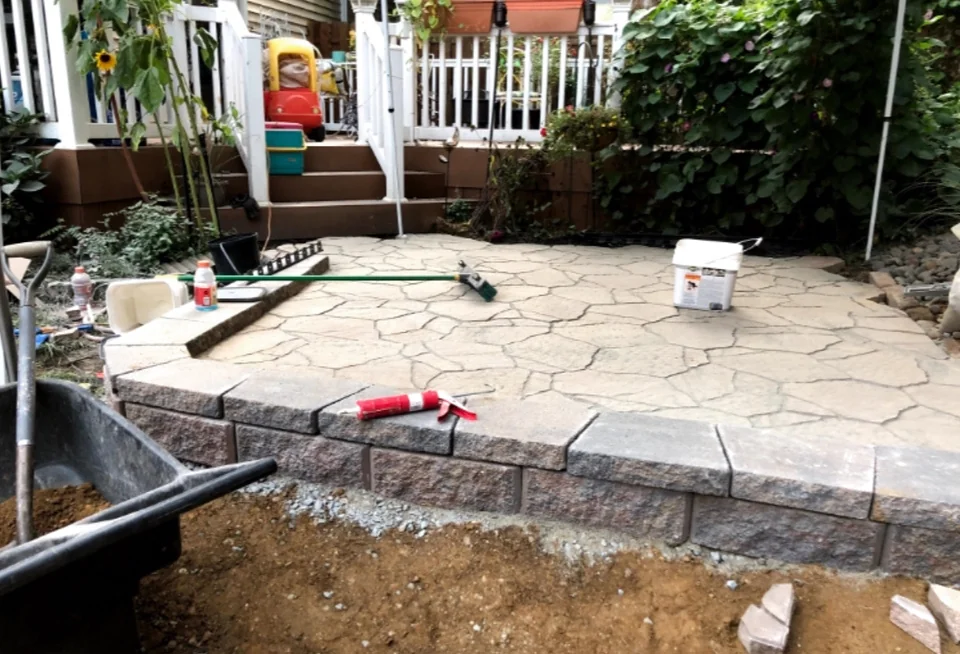 Patio installation with tools and unfinished ground still visible
