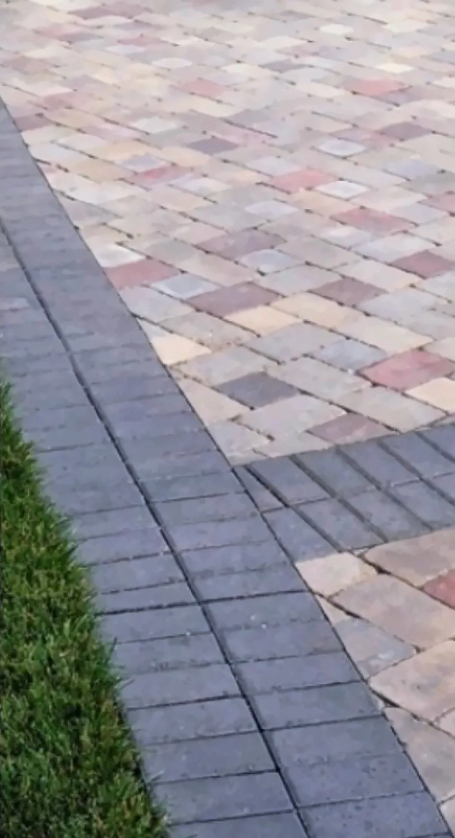Multicolor paver field meeting a charcoal paver border beside the lawn